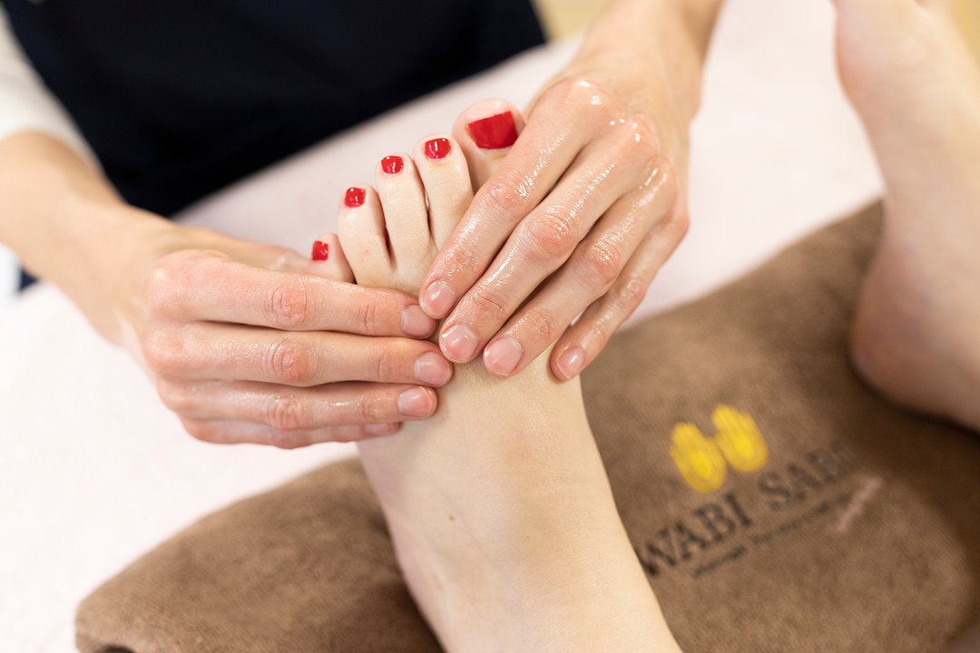 Een voetmassage op een handdoek met het Wabi Sabi-logo