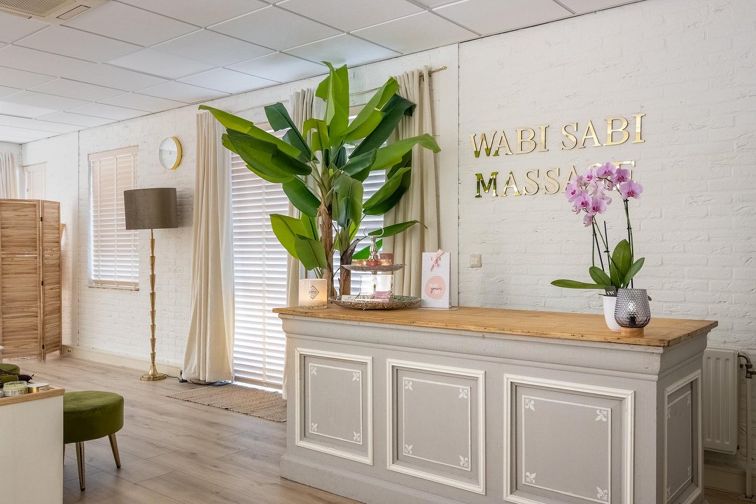 De ontvangstbalie met de gouden letters WABI SABI MASSAGE en een orchidee
