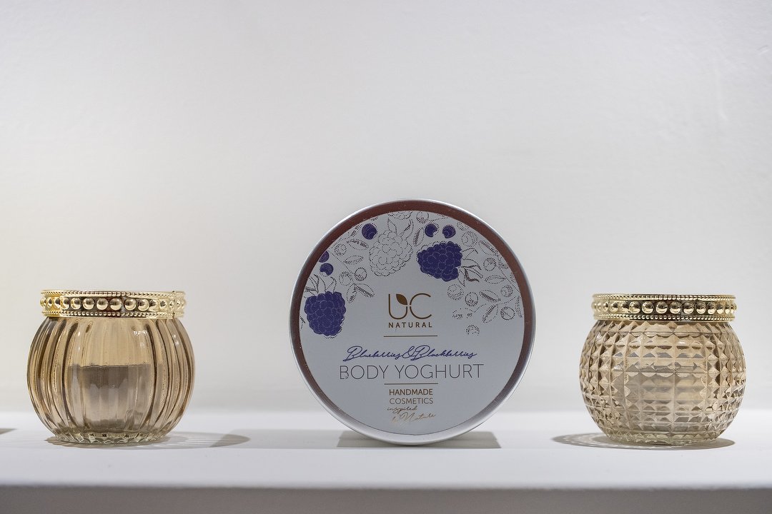 Body Yoghurt van UC Natural tussen twee gouden glazen houders