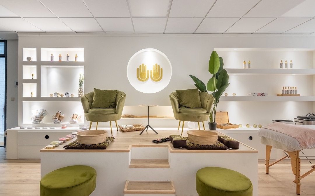 De behandelruimte Nature: twee groene fluwelen stoelen bij de voetenbaden, met de gouden handen aan de muur